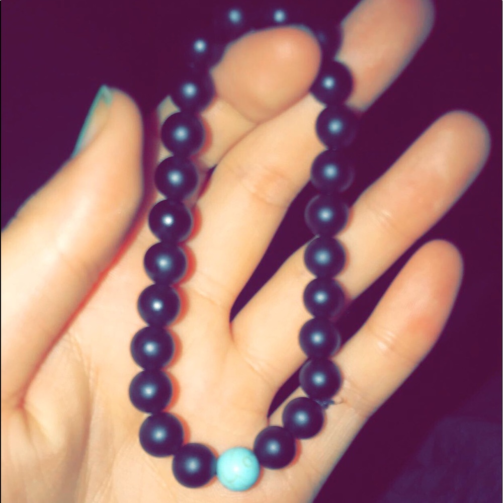 distance bracelet. black and one turquoise bead.